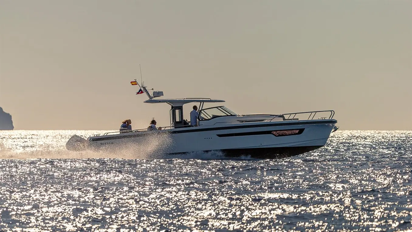 A motorboat speeds across a shimmering sea, with passengers enjoying the ride and flags displayed at the stern.